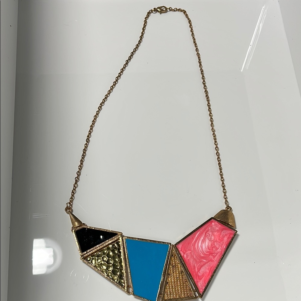 Brass color necklace with blue, black, and pink enamel.